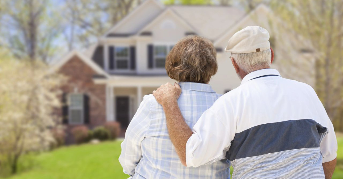 senior couple sitting outdoors facing a house